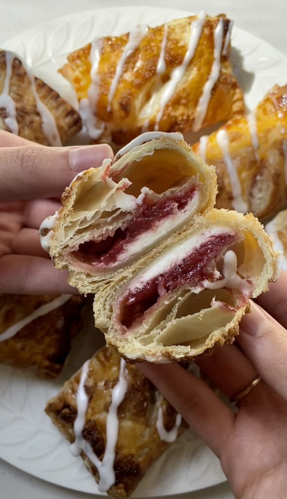 A strawberry turnover is cut open to reveal the strawberry and cream cheese filling.