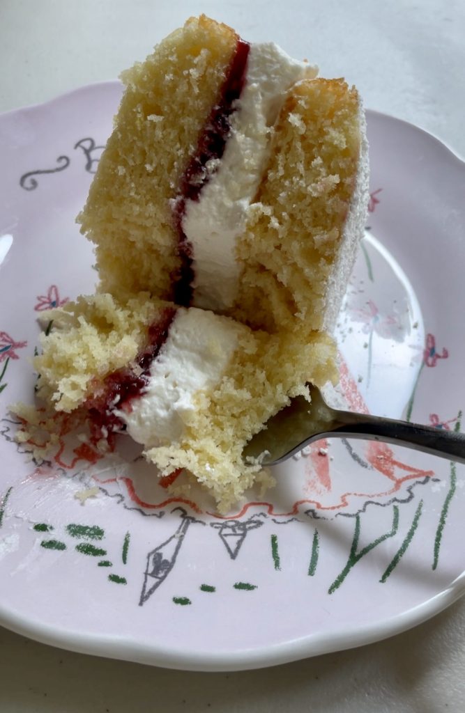 A 'bite shot' of lemon victoria sponge cake with raspberry jam and whipped cream.