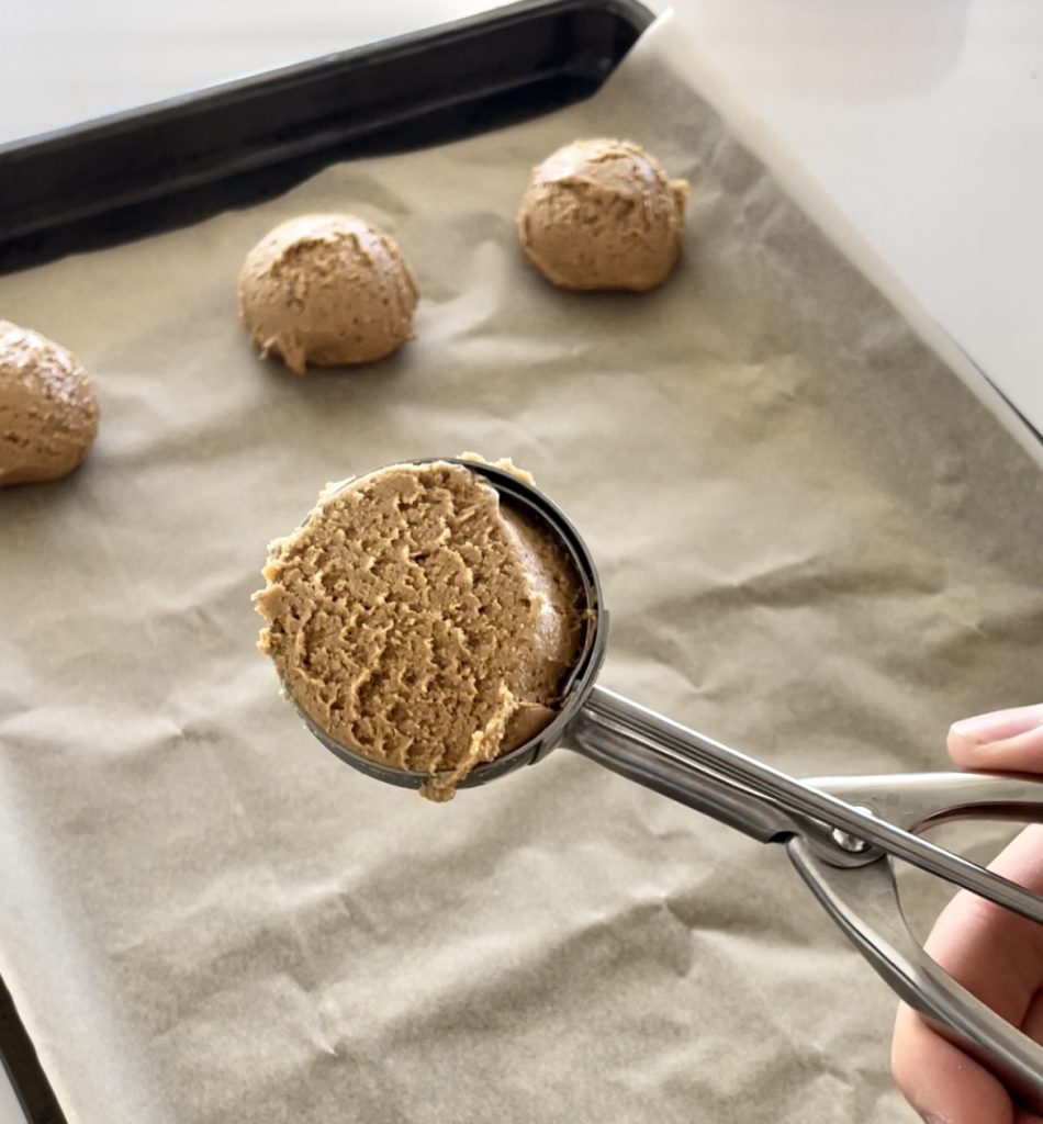 using a cookie scoop to portion out the balls of dough balls and prepare for baking.
