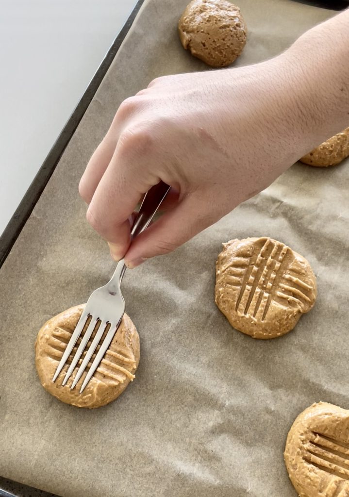 Using the prongs of a fork to create a criss-cross pattern on top of each cookie.