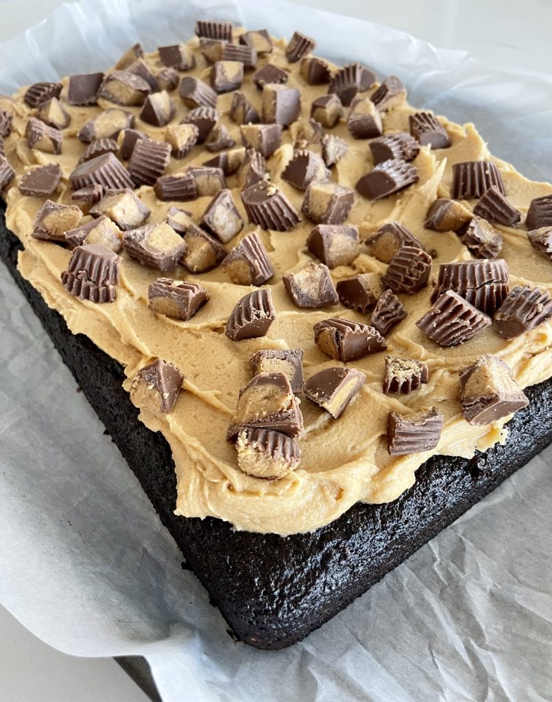 Chocolate sheet cake once baked, topped with peanut butter frosting and peanut butter cups.