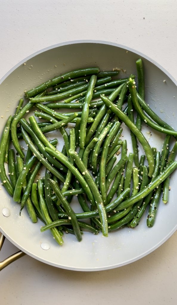 Toss the green beans in the butter sauce and cook until the garlic is fragrant.