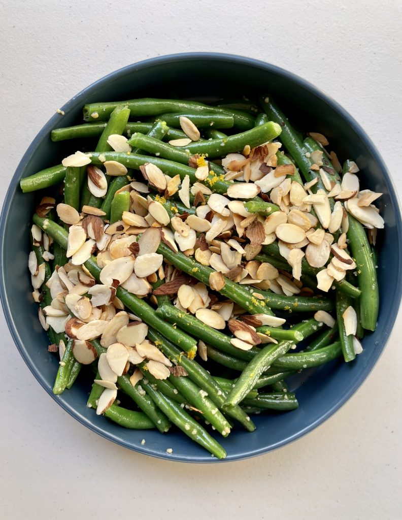 Garlic butter green beans topped with lemon zest and slivered almonds.