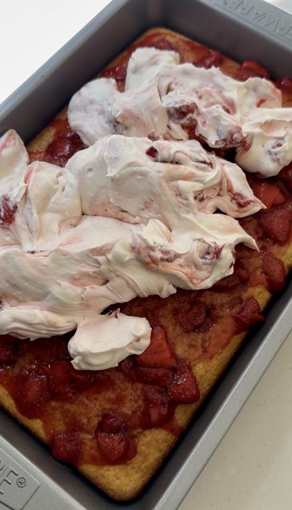 Once the strawberry poke cake is cooled, you can spread on the creamy whipped topping.