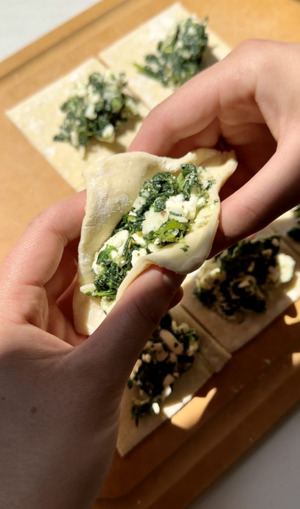 Each spinach and feta turnover will be folded into a triangle shape. Once you get the corners lined up, you'll use your fingertips to pinch the edges together. 