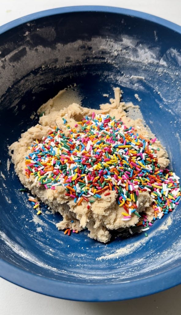 Once your cookie dough is mixed, you'll stir in the rainbow sprinkles. Feel free to use jimmies or confetti sprinkles.